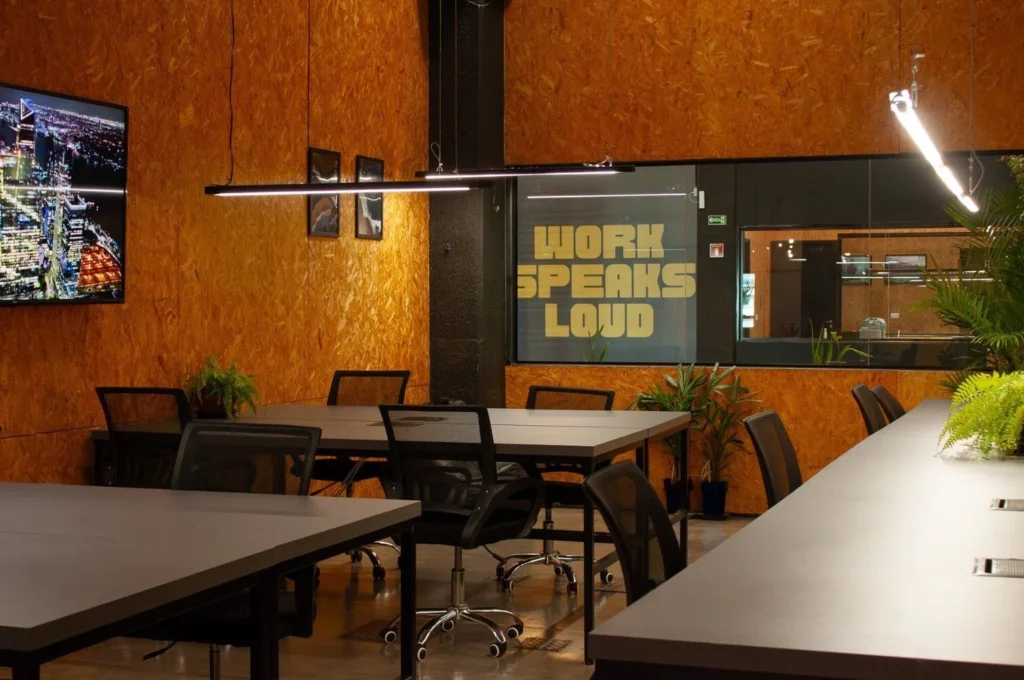 Espaço de coworking moderno da Aldeia Coworking em Curitiba com mesas compartilhadas e decoração inspiradora.