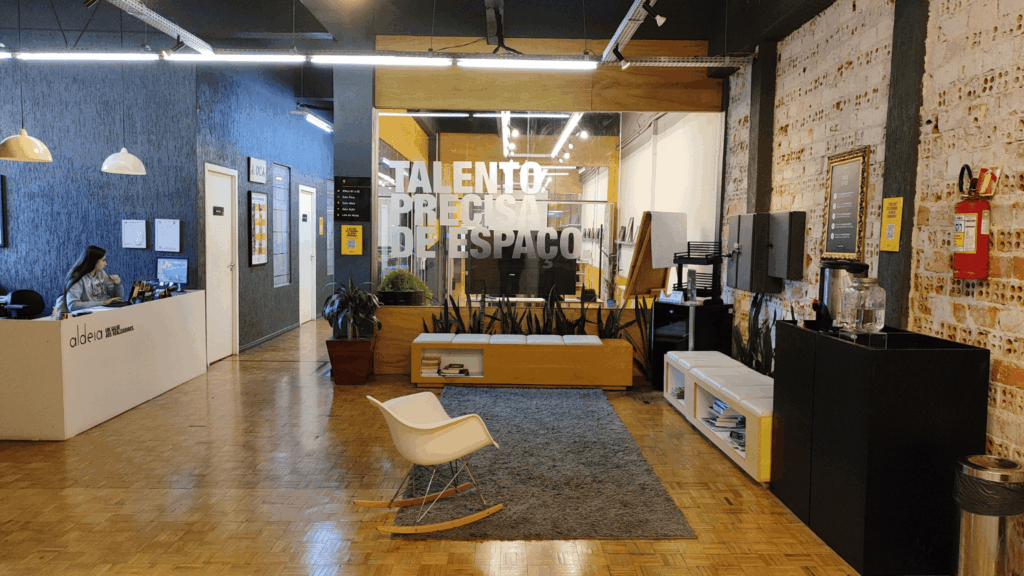 Recepção moderna da Aldeia Coworking Cândido, com ambientes aconchegantes, decoração industrial e espaço colaborativo para talentos criativos.