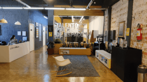 Recepção moderna da Aldeia Coworking Cândido, com ambientes aconchegantes, decoração industrial e espaço colaborativo para talentos criativos.